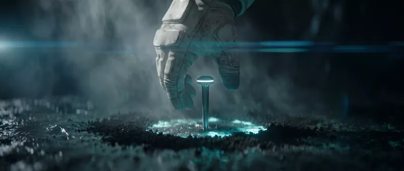 The hand lifts away from the planted beacon as a ring of turquoise light wakes around its base.