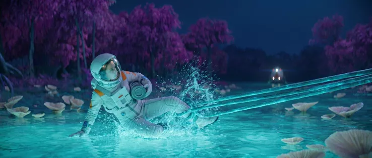 The astronaut fully down in the water, leaning back on one arm, the tendrils taut and straight, spray hanging above her